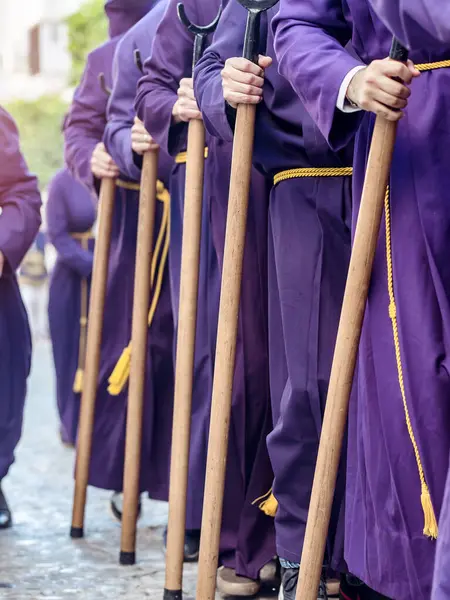 Mor cüppeli ve sarı kemerli insanlar tören sırasında tahta sopa tutuyorlar. Seçici Odaklanma.