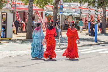 Seville, İspanya - 26 Nisan 2023: Sevilla Fuarı 'nda renkli flamenko elbiseli kadınlar.