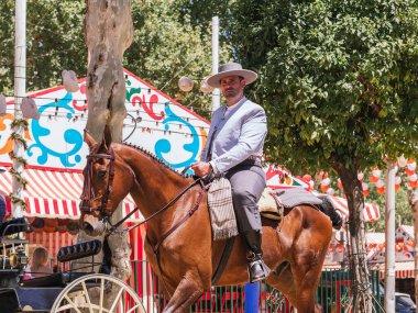 Seville, İspanya - 26 Nisan 2023: At binicisi, geleneksel kıyafetlerle süslenmiş, Sevilla Fuarı 'nın canlı ve renkli atmosferinde geçit töreni.