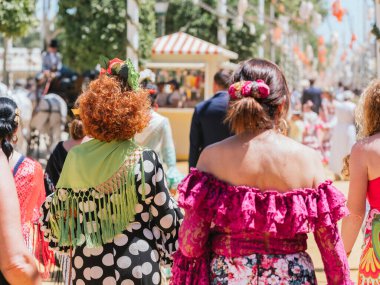 Seville, İspanya - 26 Nisan 2023: Sevilla Fuarı 'nda renkli flamenko elbiseli kadınlar.