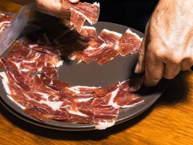 Uzman eller ustalıkla tabaktaki ince jamon dilimlerini düzenler..