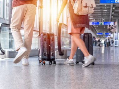 Havaalanı terminalinde elinde bavulla yürüyen tanınmayan insanların odaklanmamış fotoğrafı.