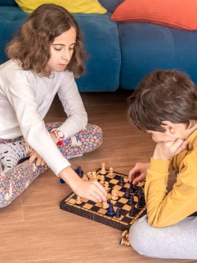 İki çocuk yerde oturup satranç oynamaya odaklanmış..
