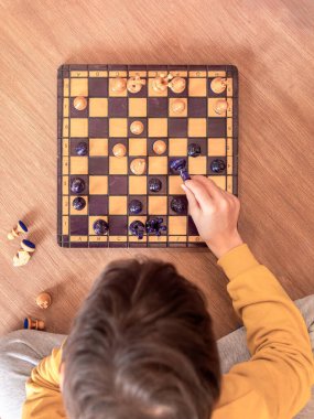 Bir çocuk yerde oturup satranç oynamaya derinden odaklanmıştı..