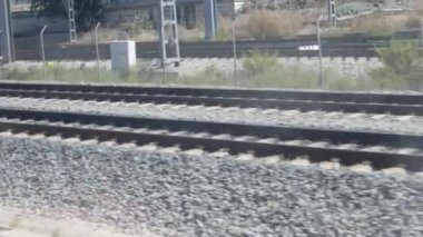 Güneşli bir günde, çakıl ağırlığıyla çevrili paralel tren raylarının manzarası..