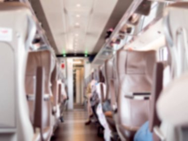 Modern bir yolcu treninin koridorunda bulanık bir görüntü. Rahat bir koltuğu ve baş üstü deposu var. Seyahat ve hareket çağrıştırıyor..