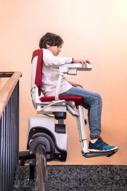 Merdiven boşluğunda yürüyen genç çocuk, engelli bireyler için ulaşılabilirlik, bağımsızlık ve destek araçlarını vurguluyor..