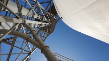 Endüstriyel silo ve metal iskeletin alçak açılı görüntüsü, açık mavi gökyüzüne ayarlanmış borular..