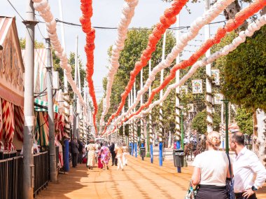 Seville, İspanya - 17 Nisan 2024: Sevilla 'daki Feria de Abril' de kavurucu güneşin altında yürüyen insanlar.
