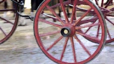Geleneksel bir panayırda klasik bir taşıma tekerleğinin yakın çekimi. Renkli flamenko elbiseli bulanık insanlar ve arka planda atlar var..