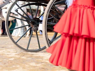 Dalgalı benekli flamenko bir elbisenin yakın çekimi, Sevilla Panayırı 'nın arka planında bir tekerlek var..