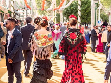 Seville, Spain - April 17, 2024 : Women in colorful flamenco dresses at the festive Seville Fair. clipart