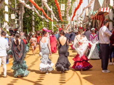 Seville, İspanya - 17 Nisan 2024: Sevilla Fuarı 'nda renkli flamenko elbiseli kadınlar.