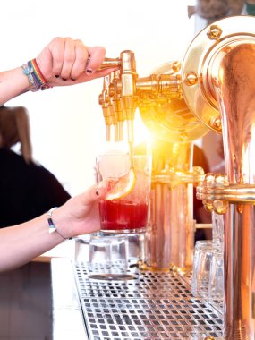 Eline renkli bilezikler takıp buzlu ve limonlu bardağa kırmızı içecek dök.