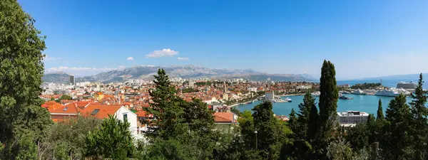 Discover the breathtaking beauty of Split city from a new perspective. A captivating panorama featuring iconic landmarks, lush trees, serene sea, and charming boats  all from the enchanting vantage point of the hilltop view.