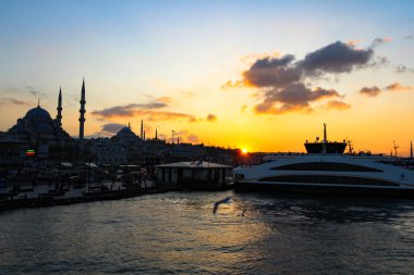 Teknelerin ve İstanbul 'un günbatımında siluetinin dramatik görüntüsü. Kitap kapakları, seyahat reklamları, takvimler ve duvar resimleri için mükemmel. Boğaz, arka plandaki yolcu gemileri ve altın saat altında ikonik liman..
