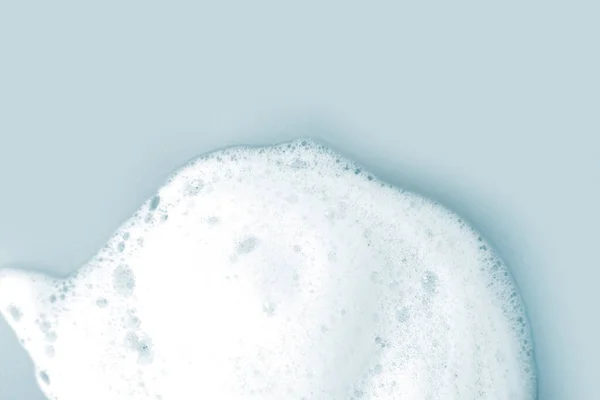 Skin care cleanser mousse foam texture. Soap, shower gel shampoo foam bubbles on light blue background