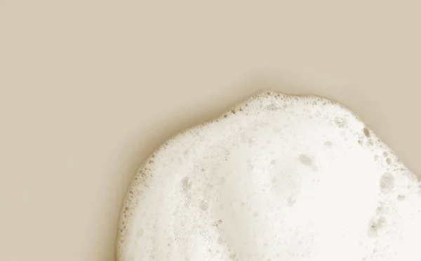 Skin care cleanser mousse foam texture. Soap, shower gel shampoo foam bubbles on beige background