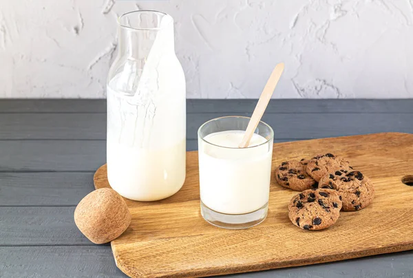 Bottle of kefir, buttermilk or yogurt, glass with wooden spoon and cookies on kitchen table