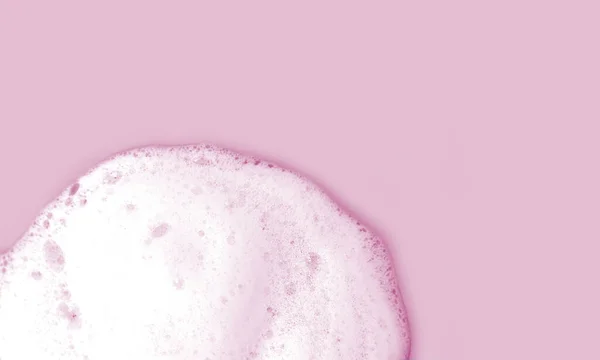 Skin care cleanser mousse foam texture. Soap, shower gel or shampoo foam bubbles on light pink background