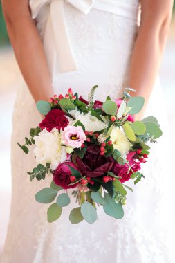 Bride holding beautiful wedding bouquet of white and burgundy peony flowers