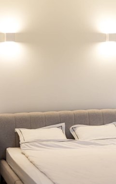 Beyaz yatak çarşafları ve yastıkları olan çift kişilik otel odası arka planında, dağınık yatak konsepti.