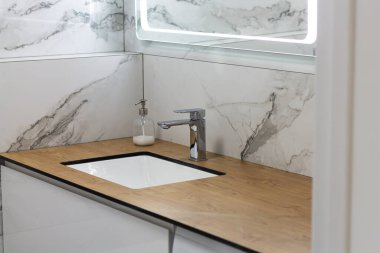 Lavabosu, musluğu ve aynası olan lüks mermer banyo.