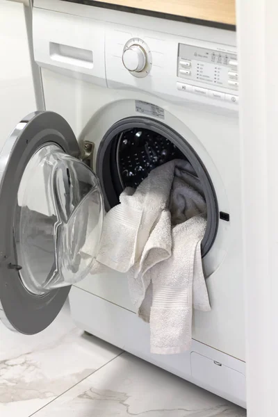 Open washing machine or clothes dryer with washed and dried white towels