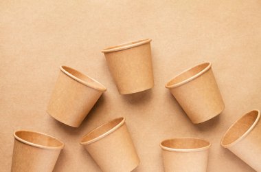 Plastiksiz ve sıfır atık konsepti. Kahverengi arkaplanda tek kullanımlık kağıt bardaklar, üst görünüm