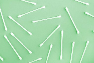 Beyaz plastik pamuk kalıpları ya da yeşil arkaplanda üst görünüm çubukları