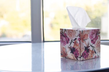 Beyaz masanın üzerinde kağıt mendiller olan kutu.