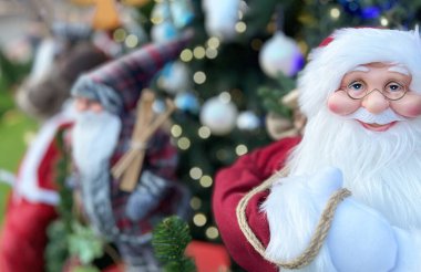 Mutlu Noel Baba bebeği Noel ağacı arka planında gülümsüyor  