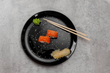 İki porsiyon somonlu suşi ve Vossabi soslu salatalık ve siyah tabakta zencefil. Üst görünüm