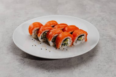 Beyaz tabakta sekiz porsiyon somon ve salatalık.. 