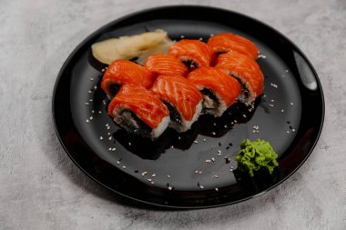 Sekiz porsiyon somon ve Vossabi soslu salatalık suşisi ve siyah tabakta zencefil.. 