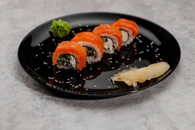 Dört porsiyon somon ve Vossabi soslu salatalık ve siyah tabakta zencefil..