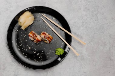 İki porsiyon karides ve Vossabi soslu yılan balığı suşisi ve siyah tabakta zencefil.