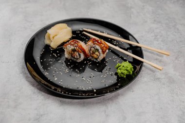 İki porsiyon karides ve Vossabi soslu yılan balığı suşisi ve siyah tabakta zencefil.