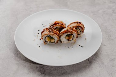 Beyaz bir tabakta dört porsiyon karides ve yılan balığı.