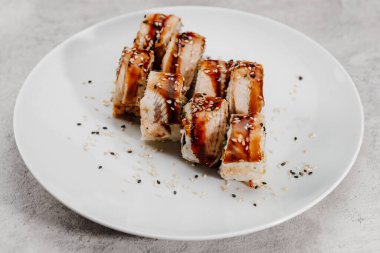 Beyaz bir tabakta sekiz porsiyon karides ve yılan balığı suşisi..