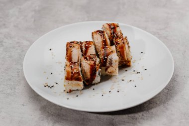 Beyaz bir tabakta sekiz porsiyon karides ve yılan balığı suşisi..