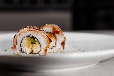 İki porsiyon suşi, beyaz tabakta karides ve yılan balığı..