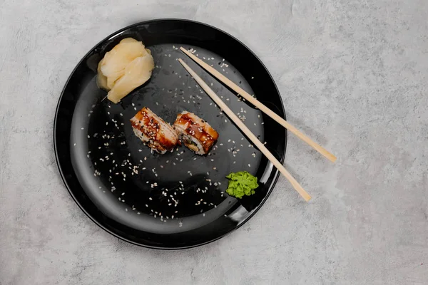 Stock image Two servings of shrimp and eel sushi with vossabi sauce and ginger on a black plate