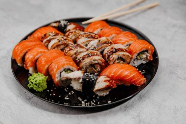 Siyah bir tabakta dört çeşit suşi. Yan görünüm.