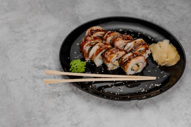 Sekiz porsiyon karides ve Vossabi soslu yılan balığı ve siyah tabakta zencefil.