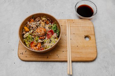 Tabakta deniz ürünleri salatası ve gri arka planda soya soslu bir kase..