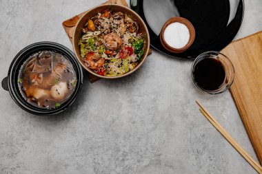 Karides udon çorbası, deniz ürünleri salatası ve gri arka planda soya sosu kasesi. Yukarıdan görüntüle