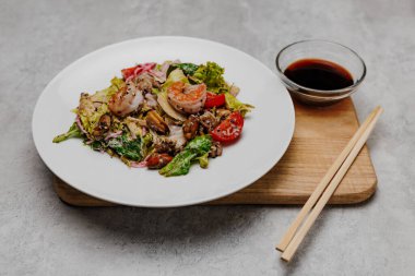 Deniz mahsullü salata ve gri arka planda soya soslu bir kase..