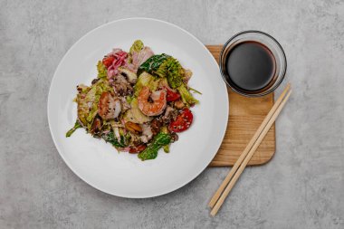 Deniz mahsullü salata ve gri arka planda soya soslu bir kase..