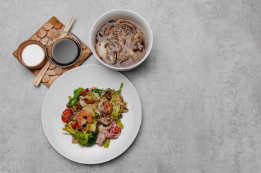 Gri arka planda karides udon çorbası ve deniz ürünleri salatası. Yukarıdan görüntüle.